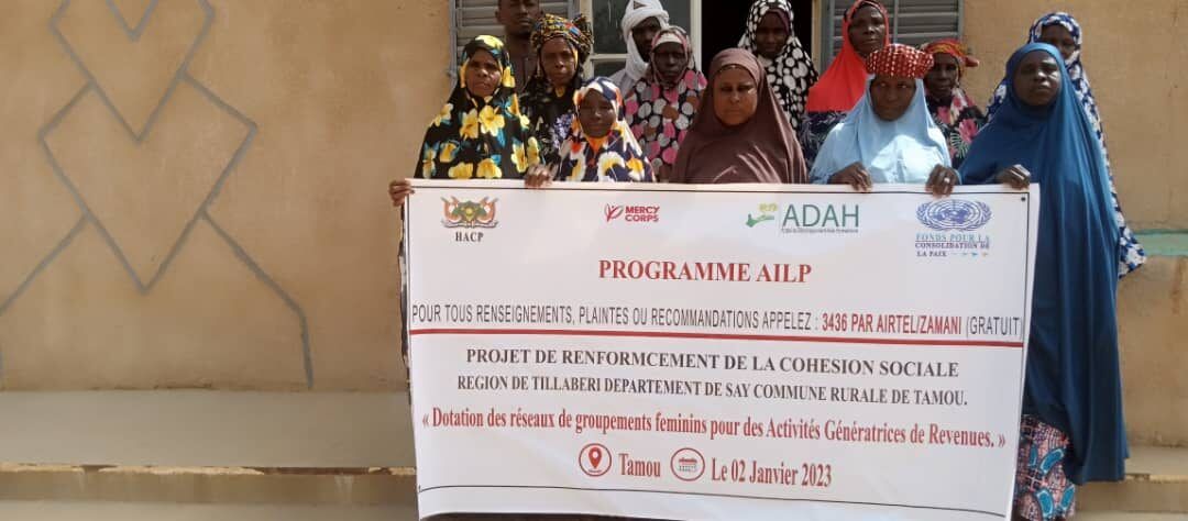 Membres des groupements féminins de Tamou tenant la banderole du programme AILP